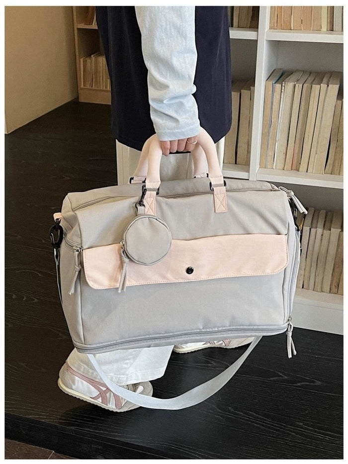 The Grey-Pink duffel held by its handles